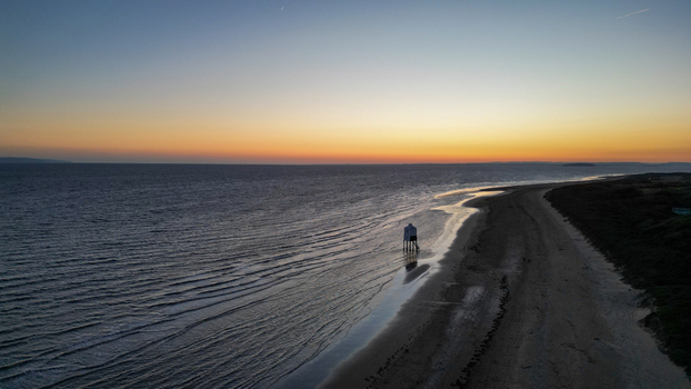 Aerial view of the Burnham on Sea Low Lighthouse standing on the sandy beach at sunset with calm sea waves and a golden horizon in Burnham on Sea England United Kingdom. Aerial view of the Burnham on Sea Low Lighthouse standing on the sandy beach at sunset with calm sea waves and a golden horizon in Burnham on Sea England United Kingdom.