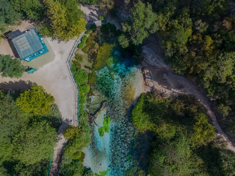 Aerial view of The Blue Eye a natural spring with vibrant turquoise water surrounded by lush green forest and walking paths in Saranda Qarku i Vlores Albania. Aerial view of The Blue Eye a natural spring with vibrant turquoise water surrounded by lush green forest and walking paths in Saranda Qarku i Vlores Albania.