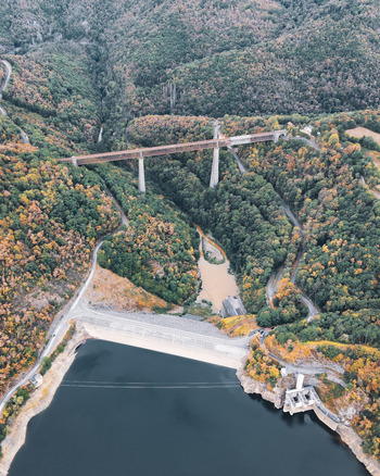 Aerial view of Fades viaduct spanning the Sioule river valley with lush autumn foliage and a dam reservoir below in Les Ancizes Comps Auvergne Rhone Alpes France. Aerial view of Fades viaduct spanning the Sioule river valley with lush autumn foliage and a dam reservoir below in Les Ancizes Comps Auvergne Rhone Alpes France.