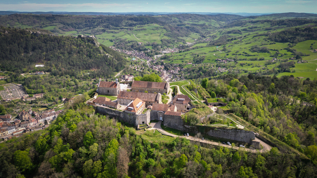 Aerial view of Fort Saint Andre with its historic stone fortifications and buildings overlooking the lush green valley and town of Salins les Bains Bourgogne Franche Comte France. Aerial view of Fort Saint Andre with its historic stone fortifications and buildings overlooking the lush green valley and town of Salins les Bains Bourgogne Franche Comte France.