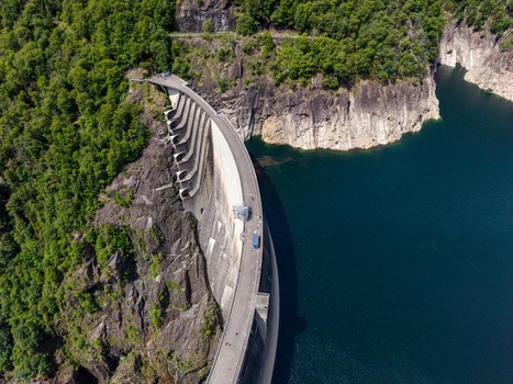 Aerial view of the Verzasca Dam with its massive curved concrete wall nestled between steep rocky cliffs and lush green forests Gordola Ticino Switzerland. Aerial view of the Verzasca Dam with its massive curved concrete wall nestled between steep rocky cliffs and lush green forests Gordola Ticino Switzerland.