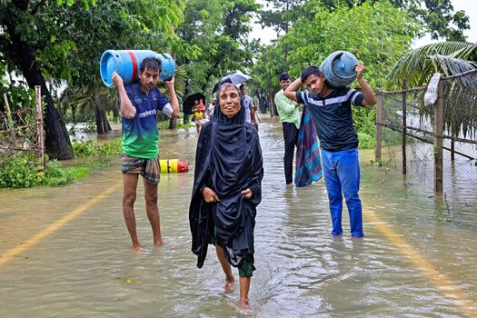 Banshkhali Upazila Chittagong Division Bangladesh 10 July 2026 View of people wading through a flooded road while carrying gas cylinders during heavy monsoon rains. Banshkhali Upazila Chittagong Division Bangladesh 10 July 2026 View of people wading through a flooded road while carrying gas cylinders during heavy monsoon rains.