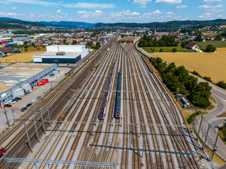 Aerial view of Daniken train station featuring multiple railway tracks trains industrial buildings and surrounding fields Daniken Solothurn Switzerland.