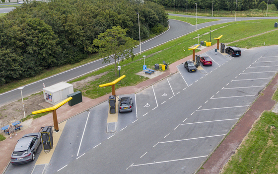 Aerial view of Fastned Charging Station with electric vehicles parked at charging points surrounded by green landscape and road infrastructure in Breukelen Utrecht Netherlands.