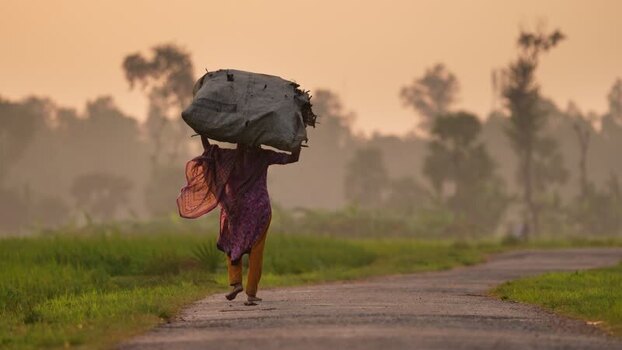 View of a woman carrying a sack on her head in Bogura Bangladesh.
