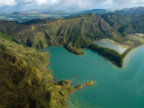 Aerial view of Lagoa do Fogo crater lake with turquoise waters surrounded by lush green volcanic ridges under a cloudy sky in Agua de Alto Azores Portugal. Aerial view of Lagoa do Fogo crater lake with turquoise waters surrounded by lush green volcanic ridges under a cloudy sky in Agua de Alto Azores Portugal.