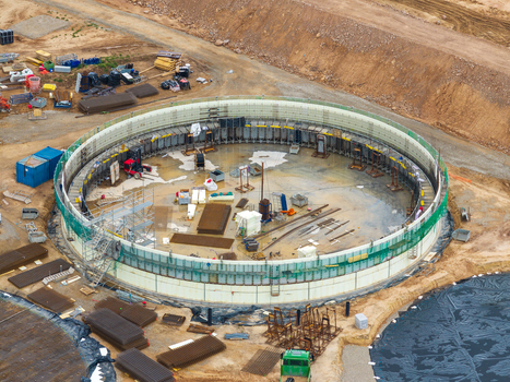 Aerial view of a circular construction site featuring steel reinforcement structures scaffolding and heavy machinery on a dirt ground in Lithuania. Aerial view of a circular construction site featuring steel reinforcement structures scaffolding and heavy machinery on a dirt ground in Lithuania.