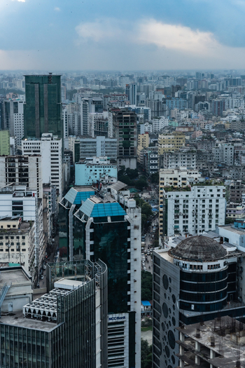 Dhaka Bangladesh 30 June 2025 Aerial view of dense urban cityscape featuring modern high rise buildings glass facade towers and bustling streets under a cloudy sky.