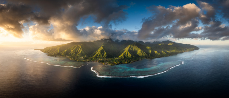 Aerial view of the lush volcanic peaks and turquoise lagoon of Moorea under dramatic sunset clouds Moorea Maiao Windward Islands French Polynesia. Aerial view of the lush volcanic peaks and turquoise lagoon of Moorea under dramatic sunset clouds Moorea Maiao Windward Islands French Polynesia.