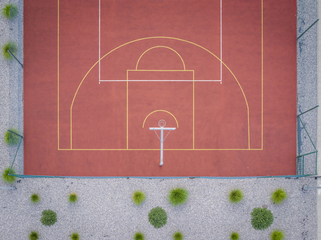 Aerial view of a basketball court with a red surface and yellow markings surrounded by a gravel border and green bushes in Wieliczka Lesser Poland Voivode Poland.