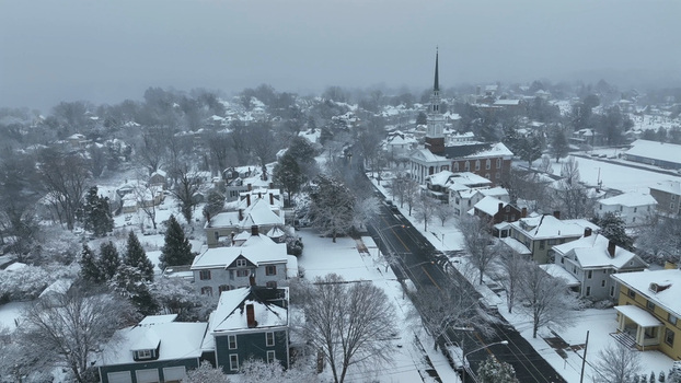 Aerial view of Rivermont neighborhood covered in fresh snow with historic houses a prominent church steeple and quiet streets under a winter sky in Lynchburg Virginia United States.