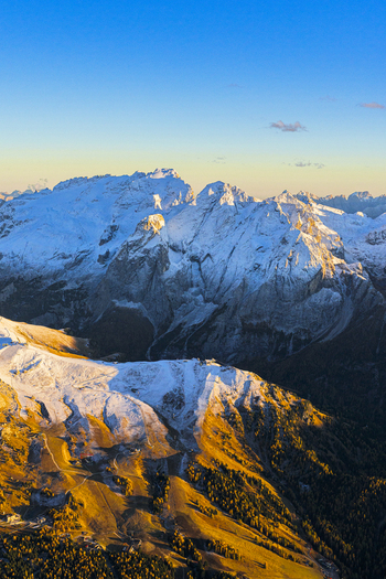 Aerial view of snow capped mountains kissed by the golden sun Marmolada glacier standing majestically against the azure sky Canazei Marmolada Italy.