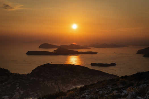 View of the sun setting over the Adriatic Sea and Elaphiti Islands with golden light reflecting on the water from the hills of Dubrovnik Dubrovnik Neretva County Croatia. View of the sun setting over the Adriatic Sea and Elaphiti Islands with golden light reflecting on the water from the hills of Dubrovnik Dubrovnik Neretva County Croatia.