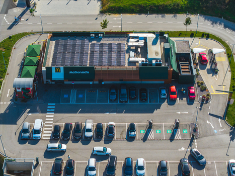 Aerial view of a McDonald s restaurant featuring a rooftop solar array and a busy parking lot with various vehicles in Allhaming Oberosterreich Austria. Aerial view of a McDonald s restaurant featuring a rooftop solar array and a busy parking lot with various vehicles in Allhaming Oberosterreich Austria.