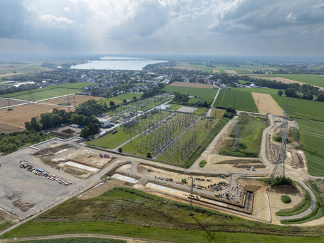 Aerial view of the Neufinsing electrical substation surrounded by green fields agricultural land and a nearby lake under a cloudy sky in Finsing Bayern Germany.
