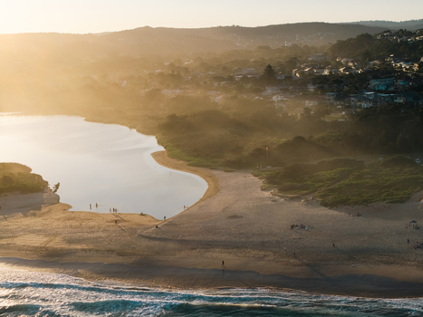 Aerial view of Dee Why Lagoon and sandy beach at golden hour with coastal vegetation and residential houses in the background in Dee Why New South Wales Australia. Aerial view of Dee Why Lagoon and sandy beach at golden hour with coastal vegetation and residential houses in the background in Dee Why New South Wales Australia.