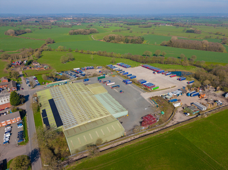 Aerial view of Ladfordfields Industrial Estate featuring a large warehouse with solar panels rows of parked semi trucks and surrounding green fields in Stafford England United Kingdom. Aerial view of Ladfordfields Industrial Estate featuring a large warehouse with solar panels rows of parked semi trucks and surrounding green fields in Stafford England United Kingdom.