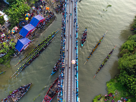 Aerial view of colorful boats clustered near the bridge where people gather contrasting with the muddy river Gopalganj Dhaka Division Bangladesh. Aerial view of colorful boats clustered near the bridge where people gather contrasting with the muddy river Gopalganj Dhaka Division Bangladesh.