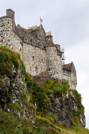 View of Duart Castle with its historic stone walls and turrets perched on a rocky cliff with green vegetation in Isle of Mull Scotland United Kingdom.