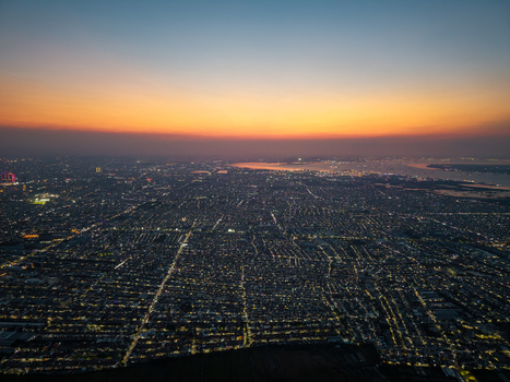 Aerial view of the sprawling cityscape of Surabaya at sunset featuring dense urban rooftops glowing street lights and the distant coastline in Surabaya East Java Indonesia.