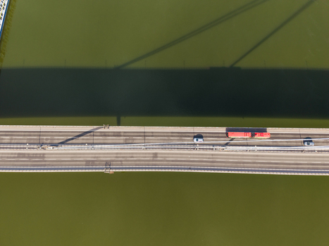 Aerial view of a bridge crossing the Danube river with cars and a red bus moving across the asphalt road in Bratislava Bratislava Region Slovakia. Aerial view of a bridge crossing the Danube river with cars and a red bus moving across the asphalt road in Bratislava Bratislava Region Slovakia.