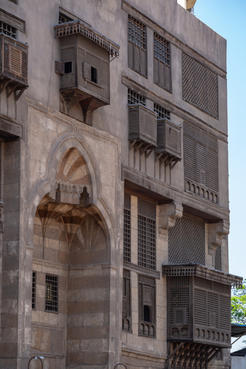 View of the intricate wooden mashrabiya windows and stone facade of the Abu Dahab Mosque in El Darb El Ahmar Cairo Governorate Egypt. View of the intricate wooden mashrabiya windows and stone facade of the Abu Dahab Mosque in El Darb El Ahmar Cairo Governorate Egypt.