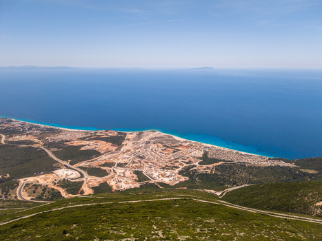 Aerial view of a coastal construction site and luxury resort development along the turquoise waters of the Ionian Sea in Palase Vlore County Albania.