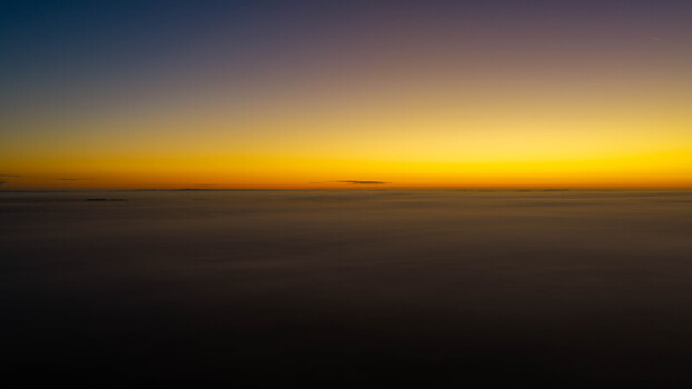 Aerial view of a vibrant sunset over a thick layer of clouds stretching to the horizon creating a serene atmosphere above Salisbury England United Kingdom. Aerial view of a vibrant sunset over a thick layer of clouds stretching to the horizon creating a serene atmosphere above Salisbury England United Kingdom.