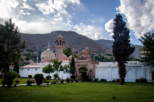 View of the historic Shahi Mosque with its distinctive domes and minarets set against a backdrop of mountains and a blue sky in Chitral Khyber Pakhtunkhwa Pakistan.