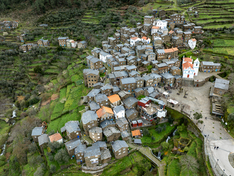 Aerial view of the village nestled on a steep slope showcasing stone houses with terracotta roofs contrasted against the white church Piódão Arganil Portugal. Aerial view of the village nestled on a steep slope showcasing stone houses with terracotta roofs contrasted against the white church Piódão Arganil Portugal.