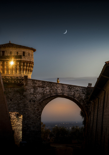 View of a beautiful medieval castle under a mystical moon at twilight Brescia Italy.