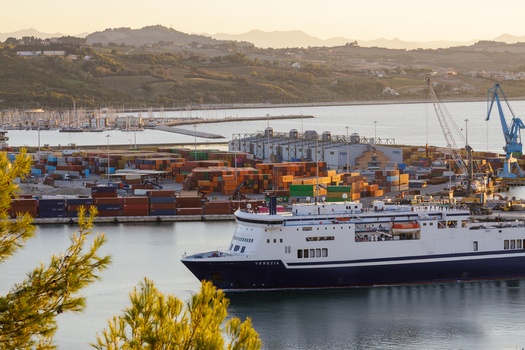 Aerial view of Ancona Port featuring the ferry ship Venezia docked near colorful shipping containers and industrial cranes under the warm glow of golden hour in Ancona Marche Italy. Aerial view of Ancona Port featuring the ferry ship Venezia docked near colorful shipping containers and industrial cranes under the warm glow of golden hour in Ancona Marche Italy.