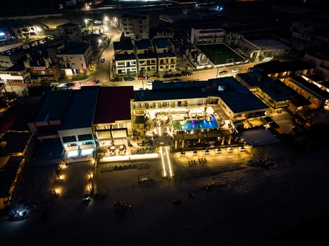 Aerial view of a luxury resort with an illuminated swimming pool and beach area at night in Ghana.