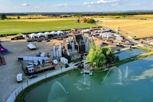 Herzogenaurach Germany 22 July 2022 Aerial view of the Open Beatz Festival main stage area with a large stage structure tents and a pond surrounded by green fields and farmland. Herzogenaurach Germany 22 July 2022 Aerial view of the Open Beatz Festival main stage area with a large stage structure tents and a pond surrounded by green fields and farmland.