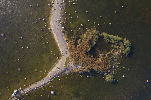 Aerial view of Kuradi saar featuring a narrow rocky spit extending into shallow coastal waters surrounded by scattered stones and reeds in Kasmu Laane Viru County Estonia.