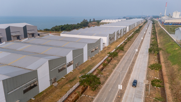 Aerial view of Kawasan Industri Terpadu Batang featuring large industrial warehouses and a long road stretching along the coast in Kecamatan Gringsing Jawa Tengah Indonesia.