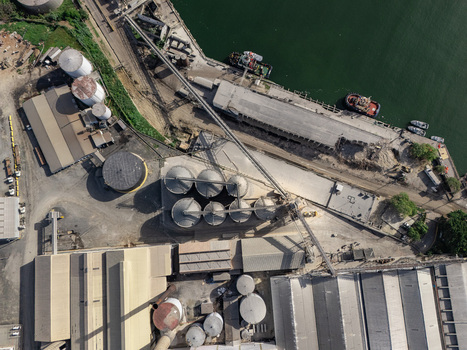 Aerial view of industrial port facilities with storage silos conveyor belts warehouses and cargo ships docked in Bajos de Haina San Cristobal Province Dominican Republic.