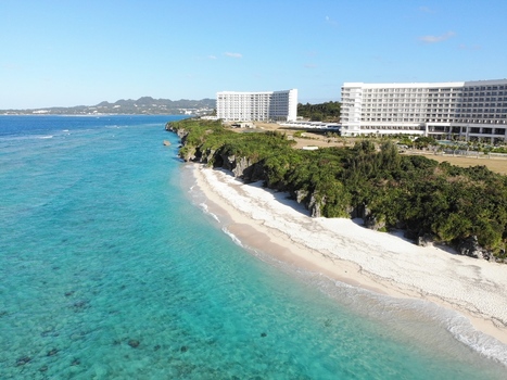 Aerial view of Sesoko Island featuring a white sand beach turquoise coral reefs and a large resort hotel nestled along the lush coastline in Motobu Okinawa Japan. Aerial view of Sesoko Island featuring a white sand beach turquoise coral reefs and a large resort hotel nestled along the lush coastline in Motobu Okinawa Japan.
