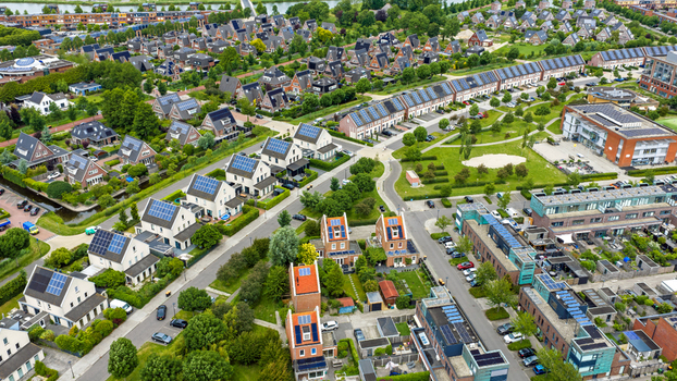 Aerial view of modern residential houses with solar panels on rooftops and green gardens in a suburban neighborhood near a canal in Heerhugowaard North Holland Netherlands. Aerial view of modern residential houses with solar panels on rooftops and green gardens in a suburban neighborhood near a canal in Heerhugowaard North Holland Netherlands.