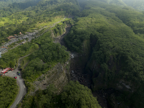 Aerial view of the deep Kali Gendol ravine and sand mine surrounded by lush tropical forests and winding roads in Kecamatan Cangkringan Daerah Istimewa Yogyakarta Indonesia. Aerial view of the deep Kali Gendol ravine and sand mine surrounded by lush tropical forests and winding roads in Kecamatan Cangkringan Daerah Istimewa Yogyakarta Indonesia.
