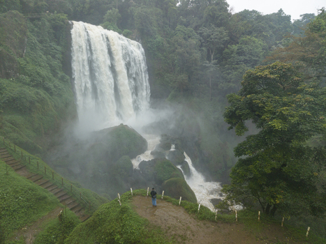 Aerial view of a majestic waterfall cascading down mossy rocks surrounded by lush greenery creating a misty spectacle Curugsewu Central Java Indonesia. Aerial view of a majestic waterfall cascading down mossy rocks surrounded by lush greenery creating a misty spectacle Curugsewu Central Java Indonesia.