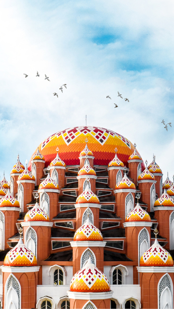 Aerial view of Masjid Kubah 99 Asmaul Husna with its distinctive colorful domes under a bright sky with birds in Kecamatan Mariso Sulawesi Selatan Indonesia.