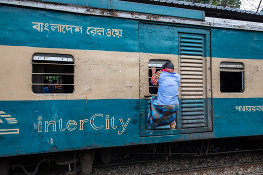 Dhaka Bangladesh 14 June 2018 View of a man climbing into a window of an interCity train carriage at Airport Railway Station. Dhaka Bangladesh 14 June 2018 View of a man climbing into a window of an interCity train carriage at Airport Railway Station.