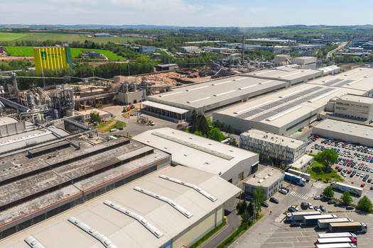 Aerial view of a large industrial complex with factory buildings warehouses and a parking lot under a clear sky in Jihlava Vysocina Region Czechia.