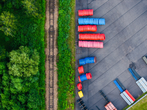 Aerial view of industrial storage area with colorful plastic pipes arranged on asphalt next to a railway track and lush green forest in Jelgava Latvia. Aerial view of industrial storage area with colorful plastic pipes arranged on asphalt next to a railway track and lush green forest in Jelgava Latvia.