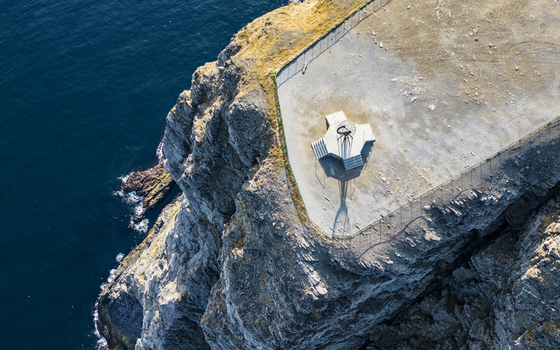 Aerial view of the iconic globe monument perched dramatically on the rugged cliffs overlooking the deep blue Arctic Ocean Nordkapp Finnmark Norway. Aerial view of the iconic globe monument perched dramatically on the rugged cliffs overlooking the deep blue Arctic Ocean Nordkapp Finnmark Norway.