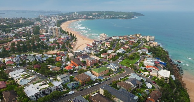 Aerial view of coastal residential suburb with houses streets and a sandy beach along the ocean in Sydney New South Wales Australia. Aerial view of coastal residential suburb with houses streets and a sandy beach along the ocean in Sydney New South Wales Australia.