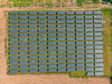 Aerial view of a large solar farm with rows of photovoltaic panels arranged in a grid pattern on a grassy field in Ogun State Nigeria.
