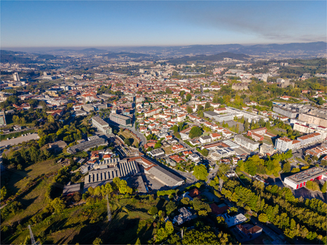 Aerial view of the historic city of Guimaraes with its dense urban fabric terracotta rooftops and surrounding green hills under a clear blue sky in Guimaraes Braga Portugal. Aerial view of the historic city of Guimaraes with its dense urban fabric terracotta rooftops and surrounding green hills under a clear blue sky in Guimaraes Braga Portugal.