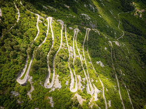 Aerial view of the famous serpentine road winding through the steep mountain slopes with lush green vegetation under bright sunlight in Kotor Kotor Municipality Montenegro. Aerial view of the famous serpentine road winding through the steep mountain slopes with lush green vegetation under bright sunlight in Kotor Kotor Municipality Montenegro.